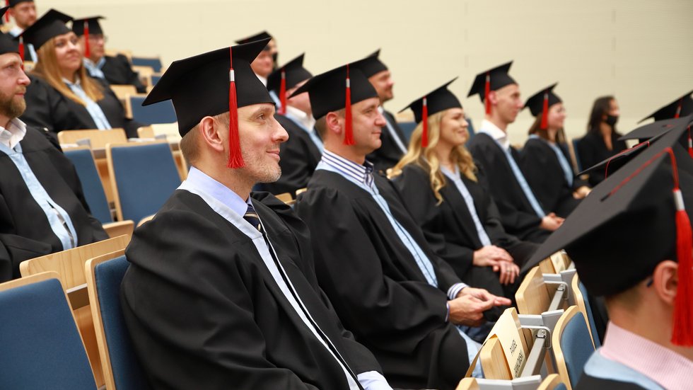 absolwenci MBA siedzą w togach i biretach na auli